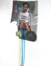 A print on fabric features a Black woman in a white T-shirt with the words “Female equals future.” Blue, yellow, and green threads hang from the bottom of the work. Une impression sur tissu représente une femme noire portant un T-shirt blanc avec les mots « Female equals future ». Des fils bleus, jaunes et verts pendent du bas de l’œuvre.