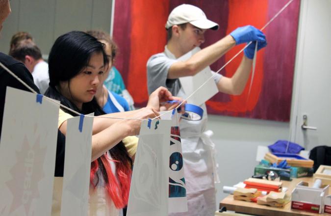 A student hangs a print up on a line hanging in the Materials Lab.