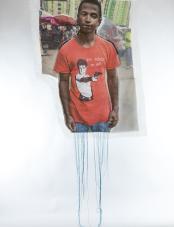 A photographic print on fabric features a Black man wearing a red T-shirt  with text that reads “You talkin’ to me?.” Blue threads hang from the bottom of the work. Une impression photographique sur tissu représente un homme noir portant un T-shirt rouge avec le texte « You talkin’ to me? ». Des fils bleus pendent du bas de l’œuvre.