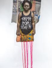 A print on white fabric features a Black woman in a black tank top that reads “Normal people scare me.” Pink, red, and orange threads hang from the bottom of the work.  Une impression sur tissu blanc représente une femme noire portant un débardeur noir avec l'inscription « Normal people scare me ». Des fils roses, rouges et orange pendent au bas de l'œuvre.